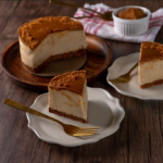 Elegant Biscoff cheesecake with a smooth, creamy filling and a rich, crumbly Biscoff biscuit base, served on a rustic wooden table with a golden fork, offering a tantalizing dessert option.